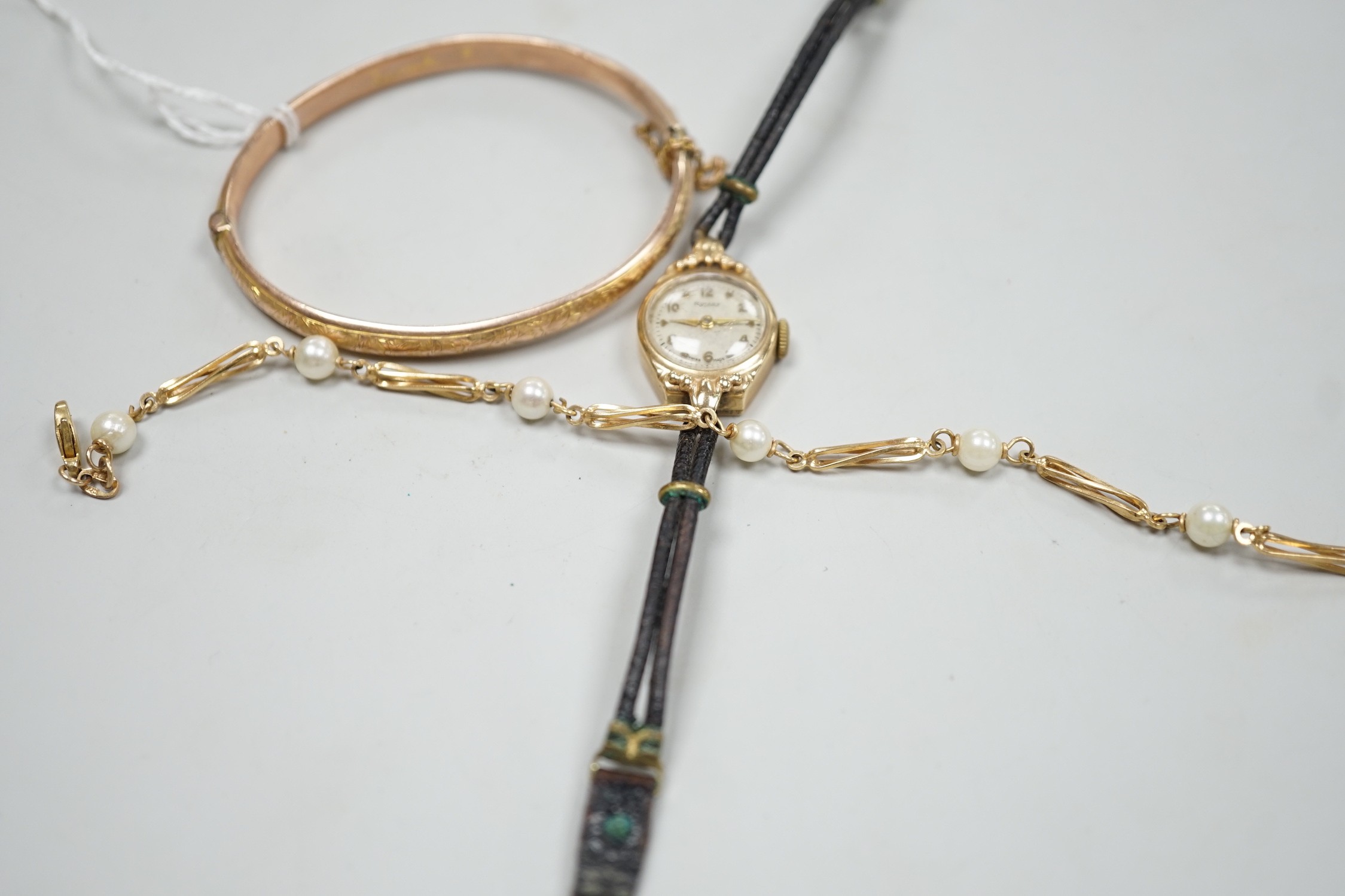 A modern 9ct gold and cultured pearl set bracelet, 18.5cm, a 9ct gold hinged bangle and a lady's yellow metal Rotary wrist watch, gross weight 21.3 grams.